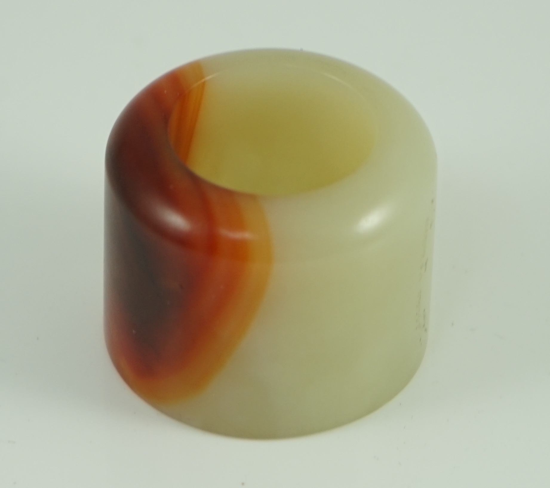 A Chinese pale celadon and russet jade archer's ring, early 20th century 3.4 cm diameter